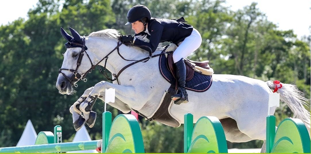 Cavaliere en veste noire franchissant un obstacle sur un cheval gris, photo de la page gamme Biarritz de