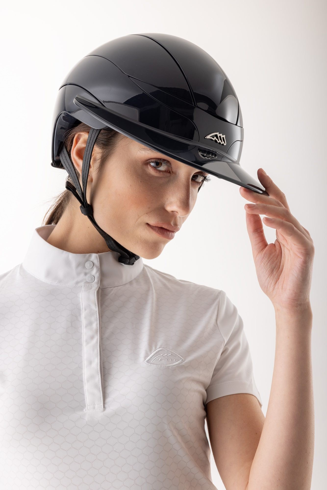 Cavaliere en polo blanc ajustant la visiere de son casque Equiline Xanto noir brillant