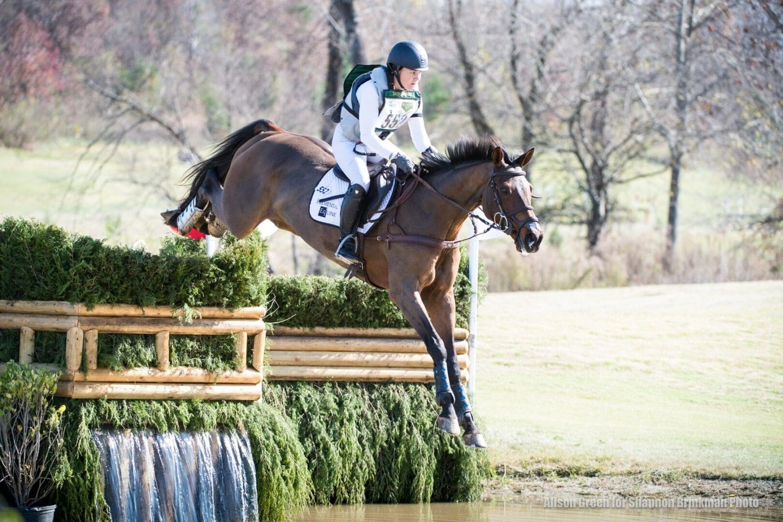 Cavalière de cross portant un gilet airbag Hit-Air, au saut d'un obstacle au-dessus de l'eau
