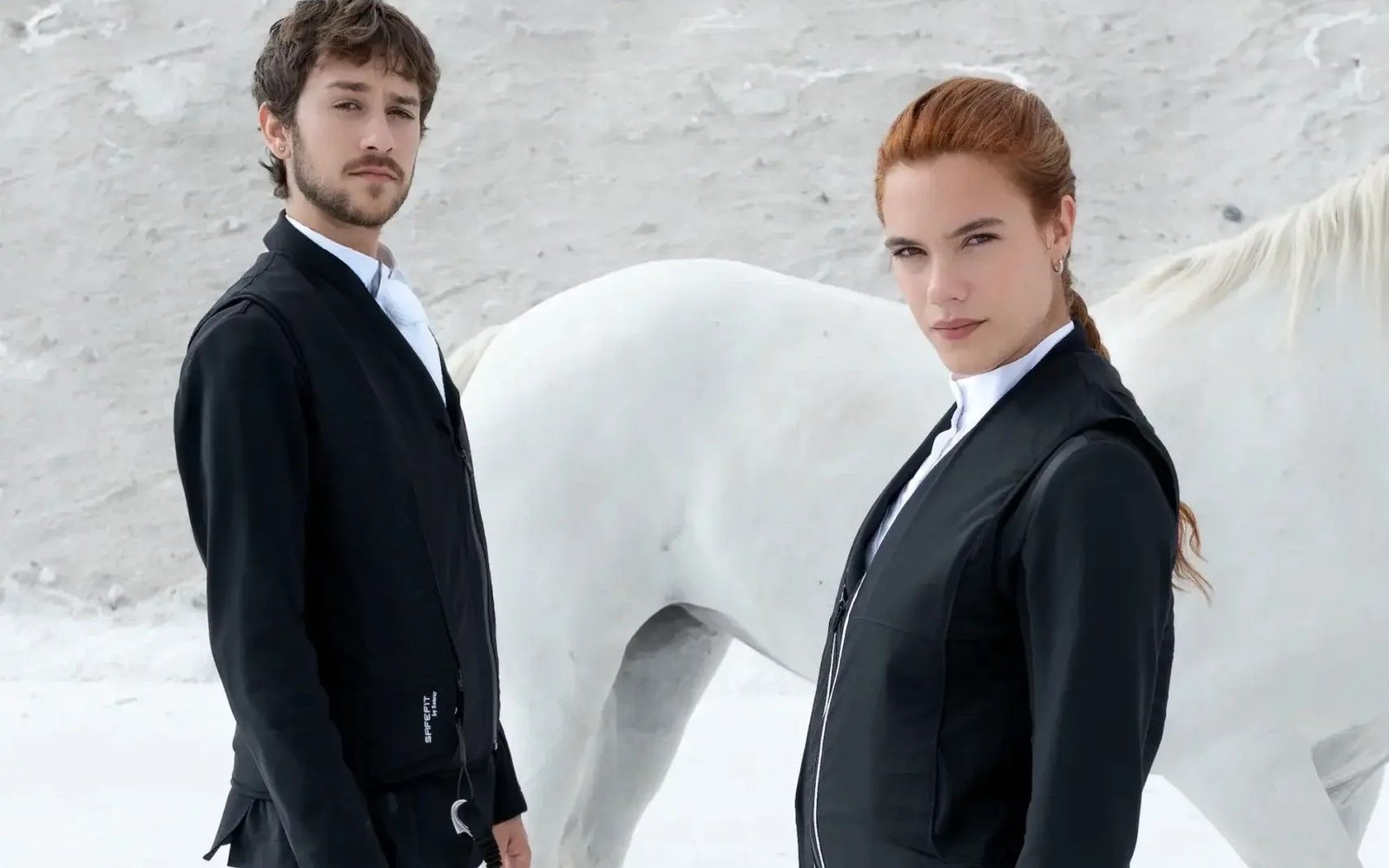 Deux cavaliers en tenue de concours portant le gilet airbag Seaver SafeFit sous leur veste, devant un cheval